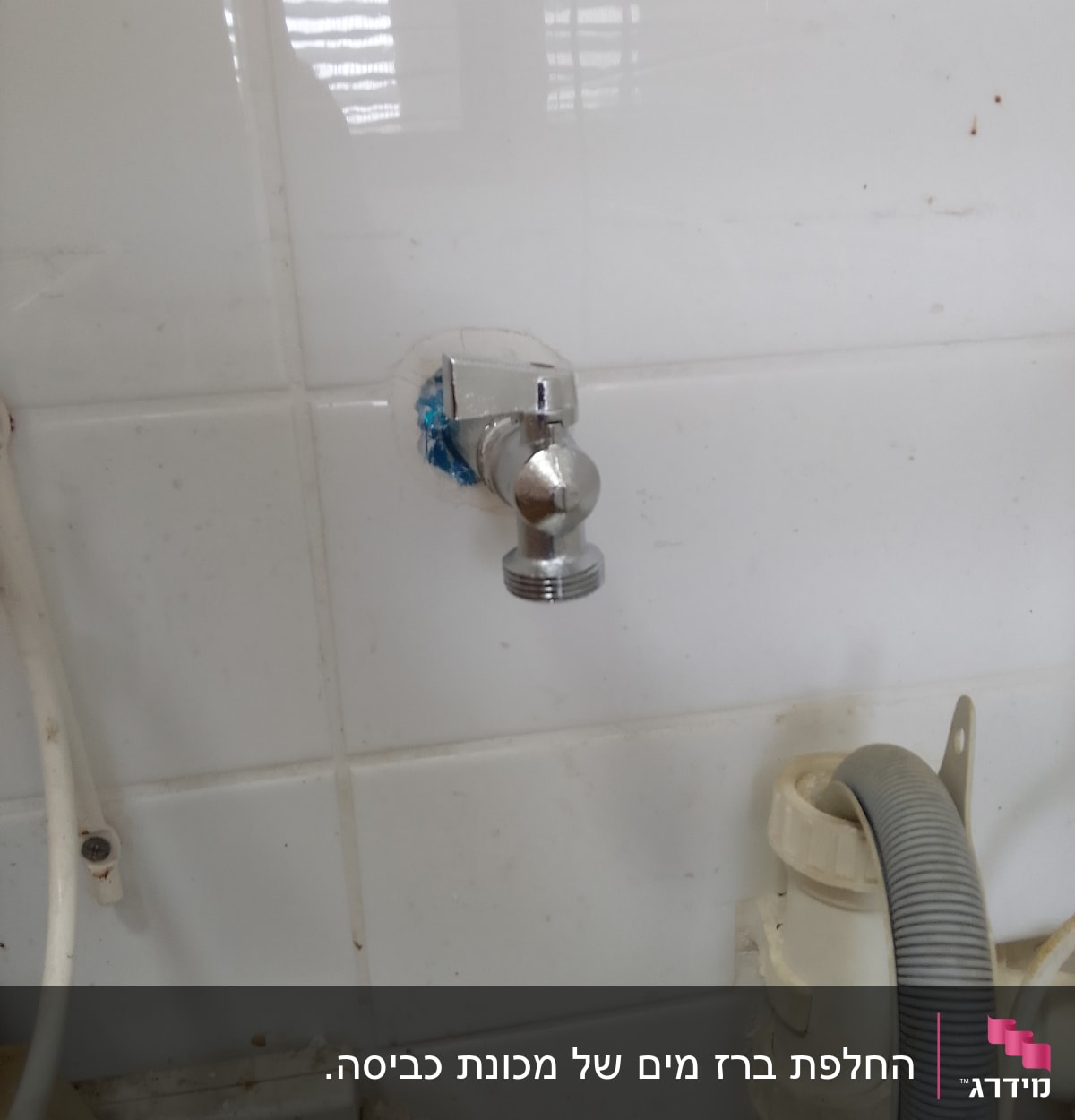 ברז מתכת מותקן על קיר אריחים לבן